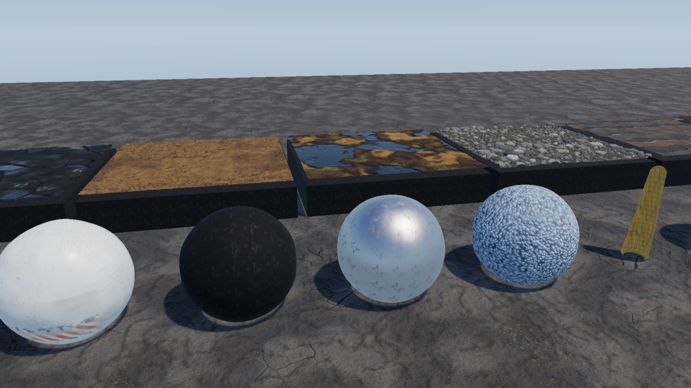Material test bench: four large spheres in white, black, chrome and speckled blue on a grey slab.